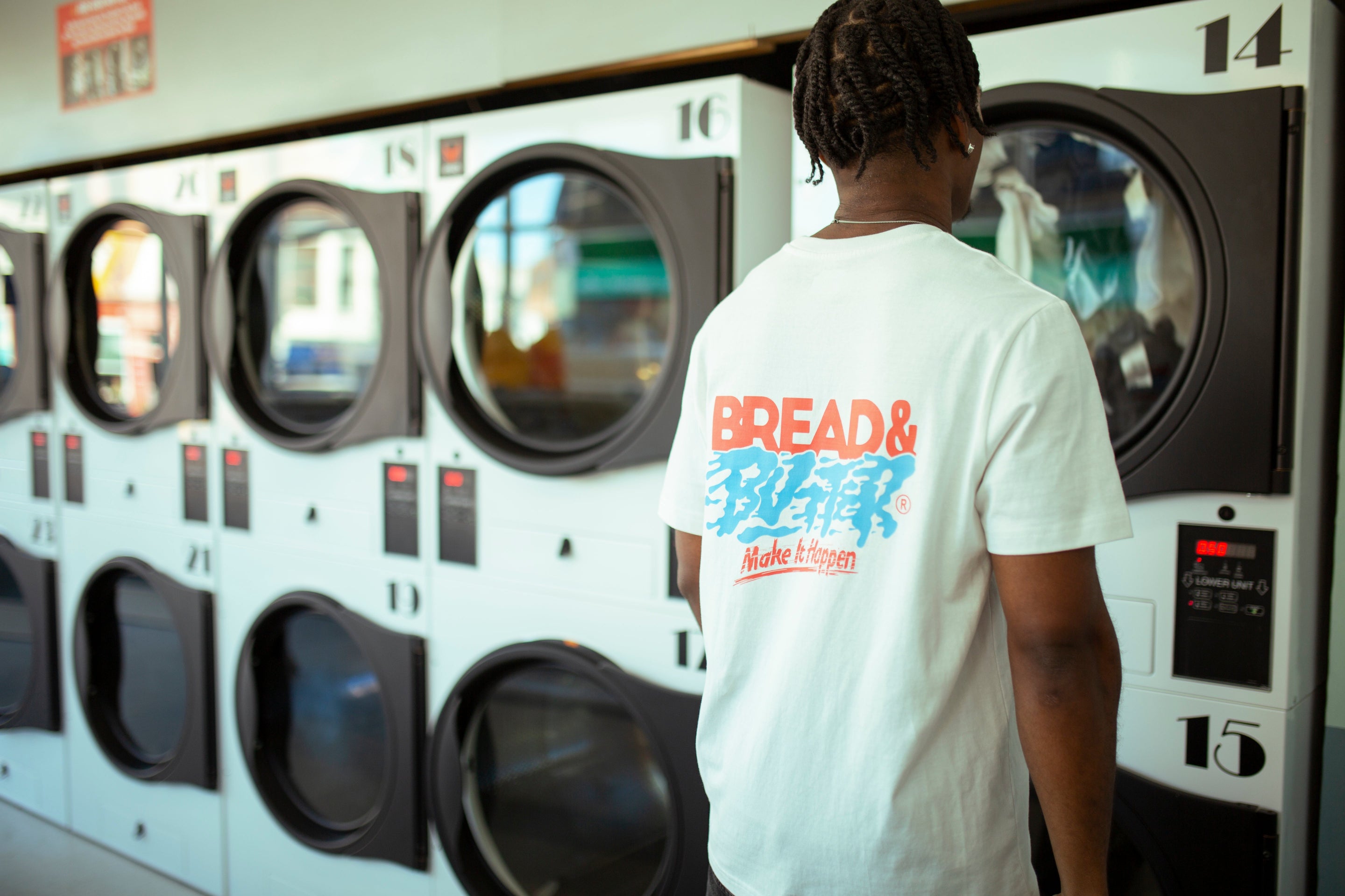 Person wearing a 'Bread & Butter' t-shirt in front of laundry machines.